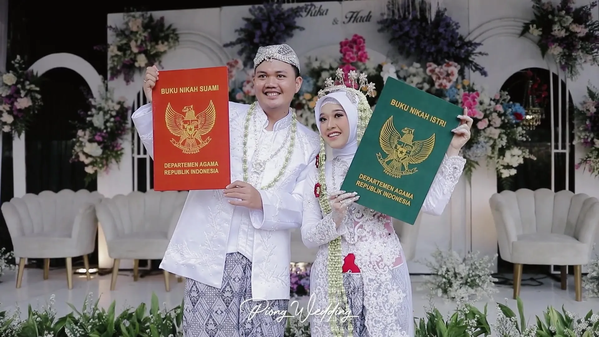 Pengantin memperlihatkan buku nikah di depan pelaminan