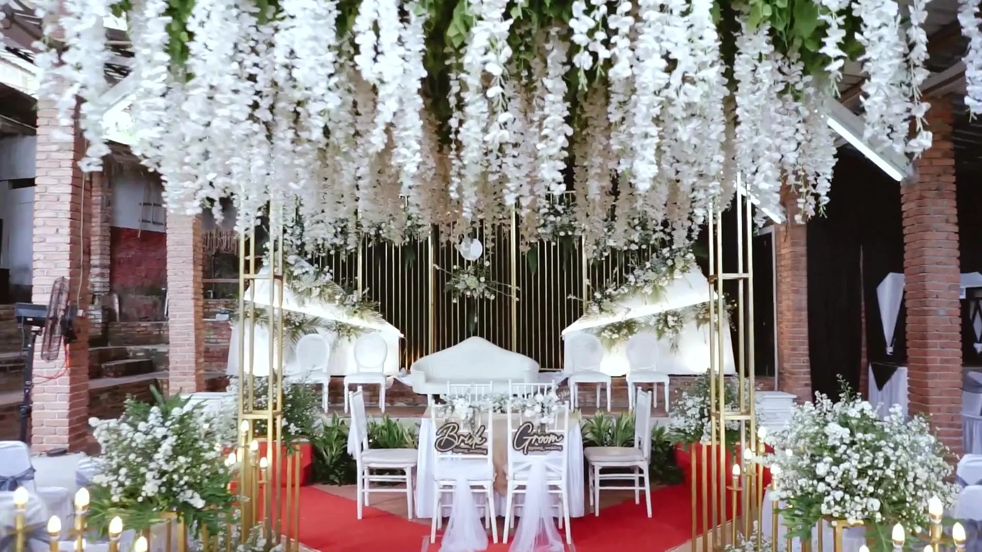 Dekorasi bunga wisteria putih menggantung di atas kursi tamu akad