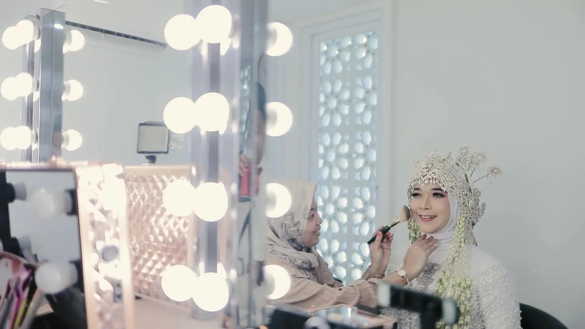 Pengantin dirias di depan cermin berlampu