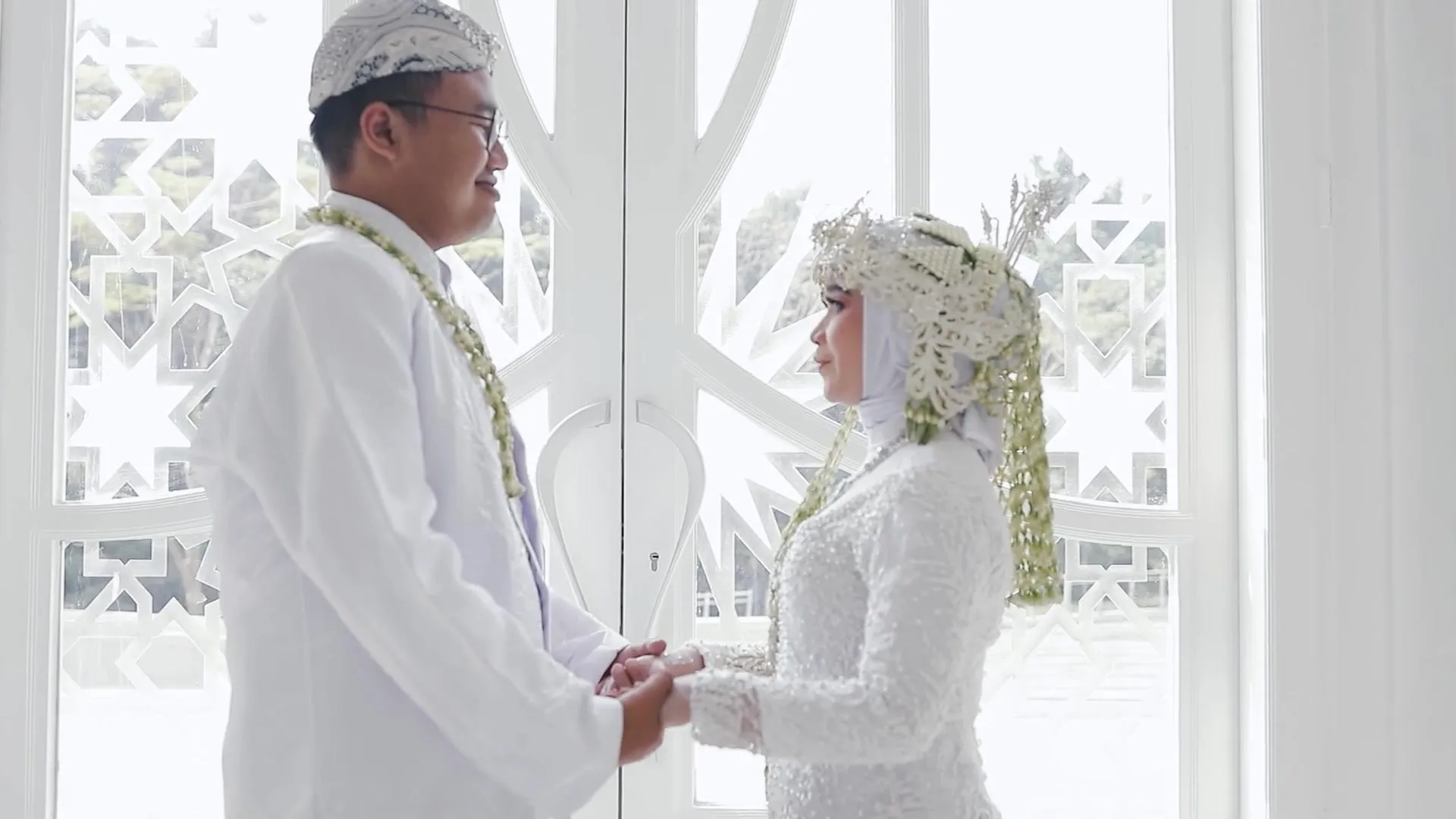Pengantin saling berhadapan di depan jendela masjid